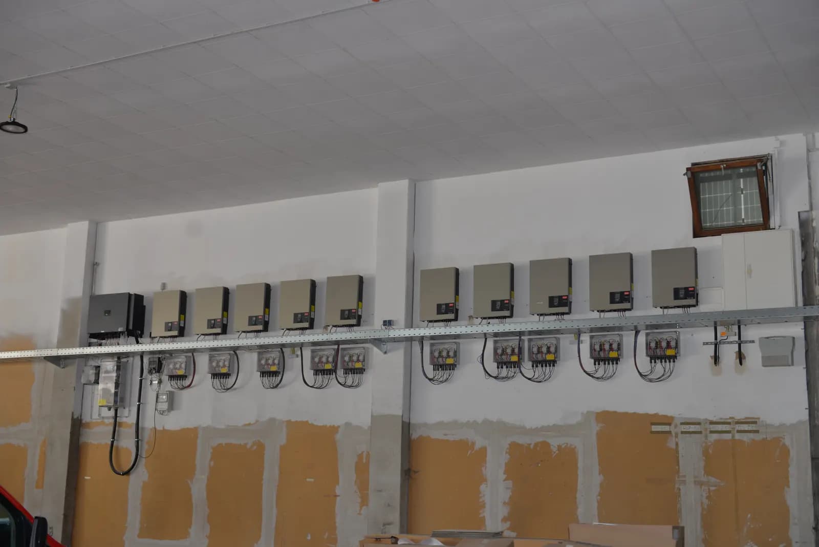 Reihe von Wechselrichtern und Zählerplätzen an der Wand einer Gewerbehalle